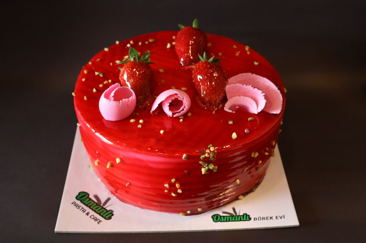 A vibrant strawberry glazed cake adorned with fresh fruit and chocolate decorations, perfect for celebrations.
